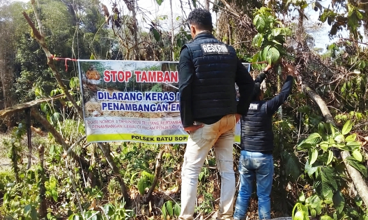 etugas Reskrim memasang spanduk peringatan keras 